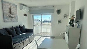 Um espaço moderno para relaxar, com sofá, mesa de jantar e televisão.