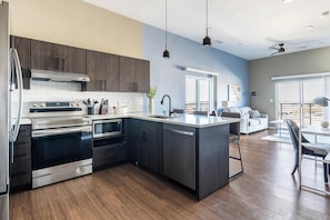 A modern kitchen with stainless steel appliances, a central island, and a dining area with a view.