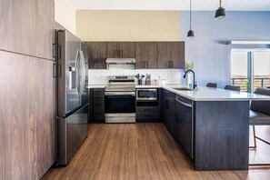 A modern kitchen with stainless steel appliances, dark wood cabinetry, and a large island with seating.