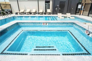 A swimming pool with a 3 FT depth limit sign, lounge chairs, and a no diving sign.