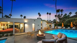 A modern outdoor pool area with a fire feature, lounge seating, and a dining area. - Central Palm Springs | Pool | Hot Tub (Palm Springs)