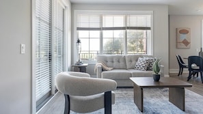A living room with a grey sofa, a round armchair, a coffee table, and a potted plant. - Landing | Spectacular 2BD, Gym, Yoga Studio (Savannah)