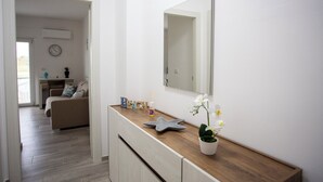 Egy modern fürőszoba, melyben fa mosdókagyló, nagy tükör és virágzó orchidea található cserépben.