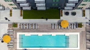 Vista aérea de uma área de piscina no terraço, com piscina retangular, espreguiçadeiras e guarda-sóis.