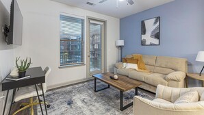 Un salon moderne avec un canapé, une table basse et un bureau agrémenté d’une plante.