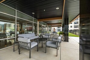 Un espace extérieur aménagé avec des meubles modernes, de grandes fenêtres et une vue sur les bâtiments environnants.