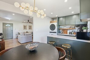 Una cucina moderna con lavatrice integrata, un'area pranzo con tavolo rotondo e un bancone con sgabelli.