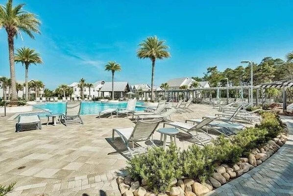 A poolside area with lounge chairs, a swimming pool, and palm trees. - Poolside Resort with Golf Cart & Bikes (Watersound)