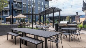 An outdoor patio area with tables and chairs, a barbecue grill, and a pergola. - Landing | Stylish 2BD, Gym, Yoga Studio (Colorado Springs)