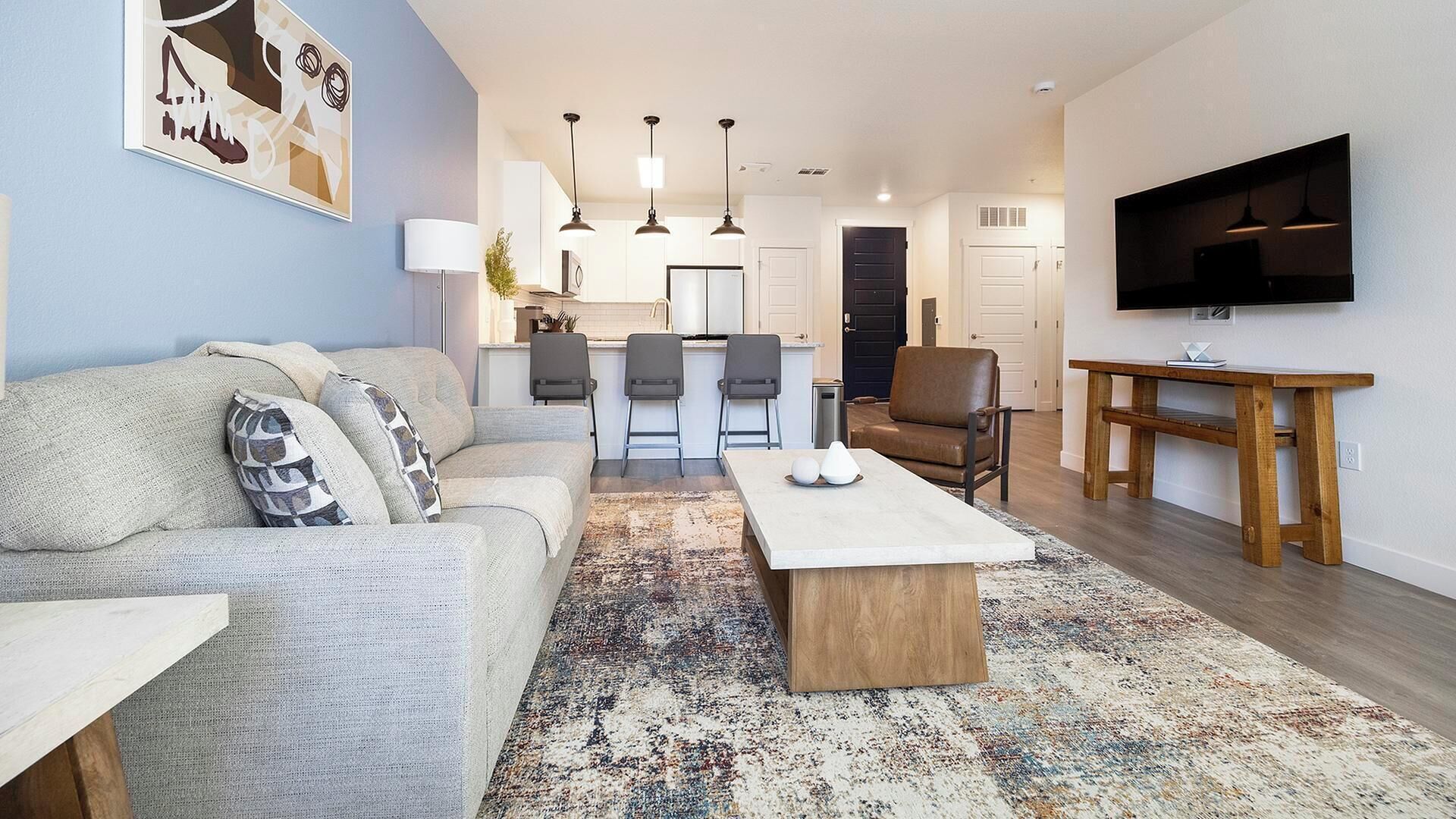 Een moderne woonkamer met een bank, salontafel en een televisie op een houten dressoir.