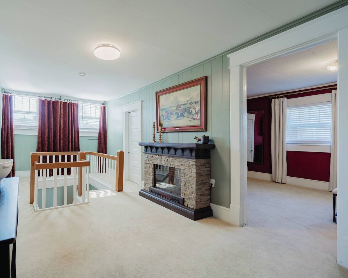 A room with a fireplace, a painting, and a view of a balcony.