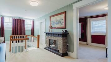 A room with a fireplace, a painting, and a view of a balcony.