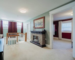 Una habitación con chimenea, un cuadro y vistas a un balcón.