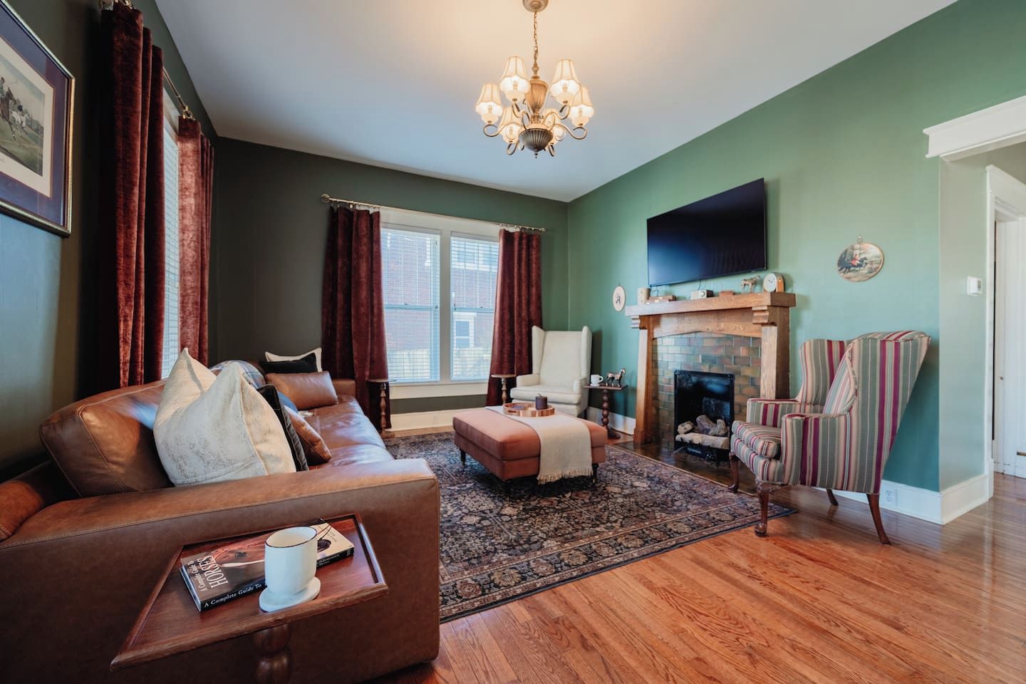 Een woonkamer met een leren bank, een open haard, een televisie en een gestreept fauteuil.