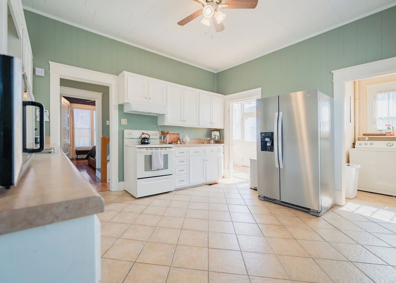 Una cocina moderna con armarios blancos, un refrigerador de acero inoxidable y piso de baldosas.
