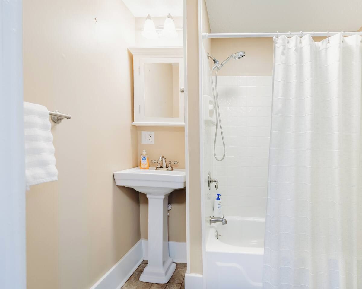 Un baño con lavamanos, espejo y ducha.
