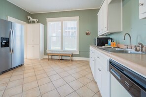 Eine Küche mit Kühlschrank, Mikrowelle, Spüle und einem Fenster mit Jalousien.