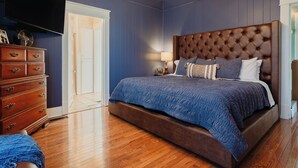 Un dormitorio con una cama grande, cómoda de madera y televisión montada en la pared.