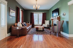 A living room with a brown leather sofa, a striped armchair, and a wooden coffee table. - New listing! Historic 4 bedroom home in Russellville! (Russellville)