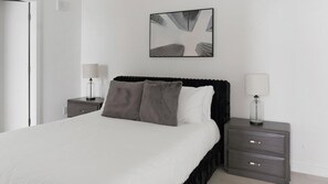 A neatly arranged bedroom with a bed, two bedside tables, and a wall-mounted artwork. - Landing | Stylish 2BD, Gym, Yoga Studio (Durham)