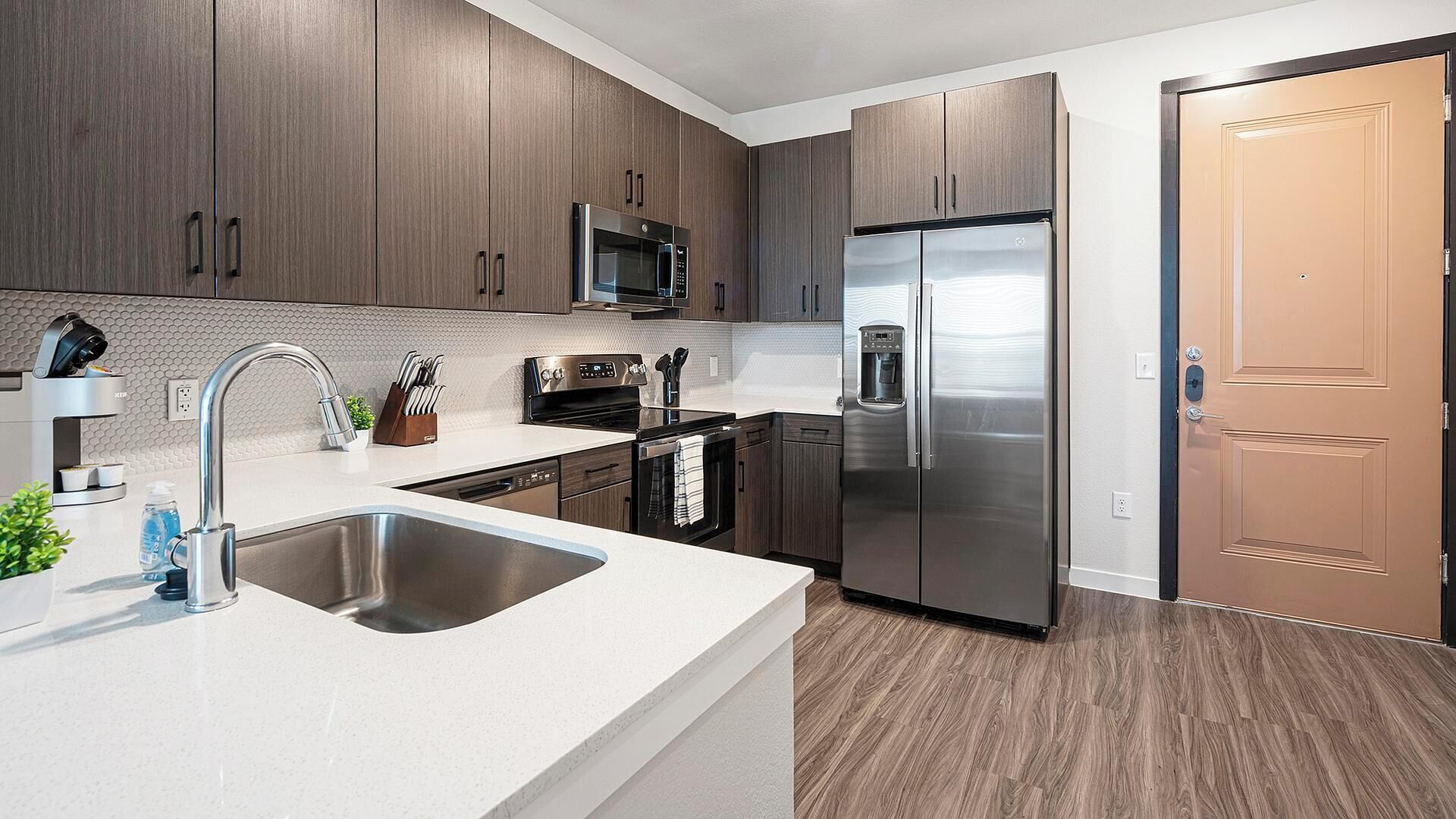A modern kitchen with stainless steel appliances, a double sink, and wooden cabinetry.