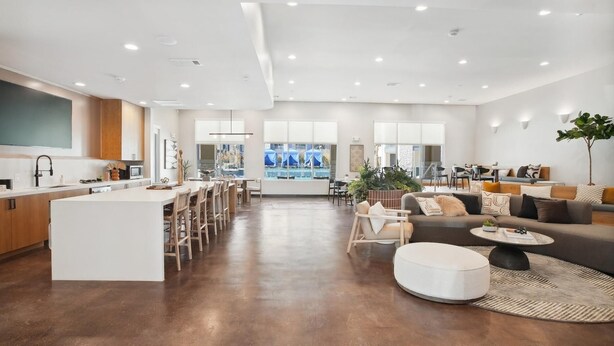 Een ruime woonkamer met een keuken, eethoek en zithoek met een bank en salontafel.