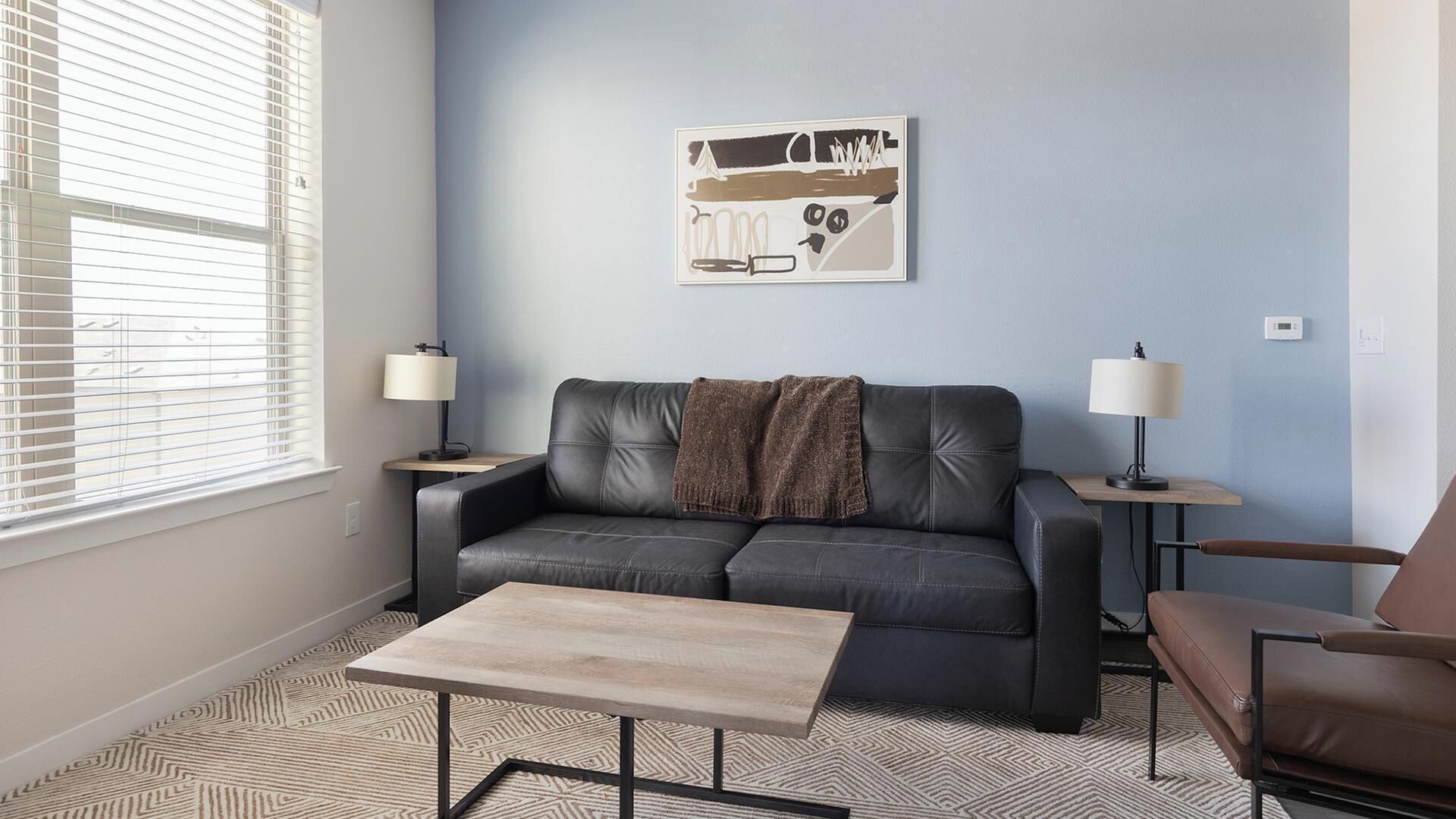 A modern living room with a leather sofa, a coffee table, and two side tables with lamps.