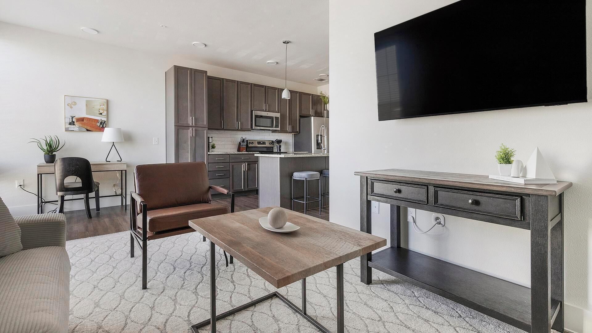 A modern living space with a dining area, a kitchen, and a TV mounted on the wall.