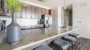 Eine moderne Küche mit Granit Arbeitsplatte, Edelstahlgeräten und einer Bar mit Sitzgelegenheiten.