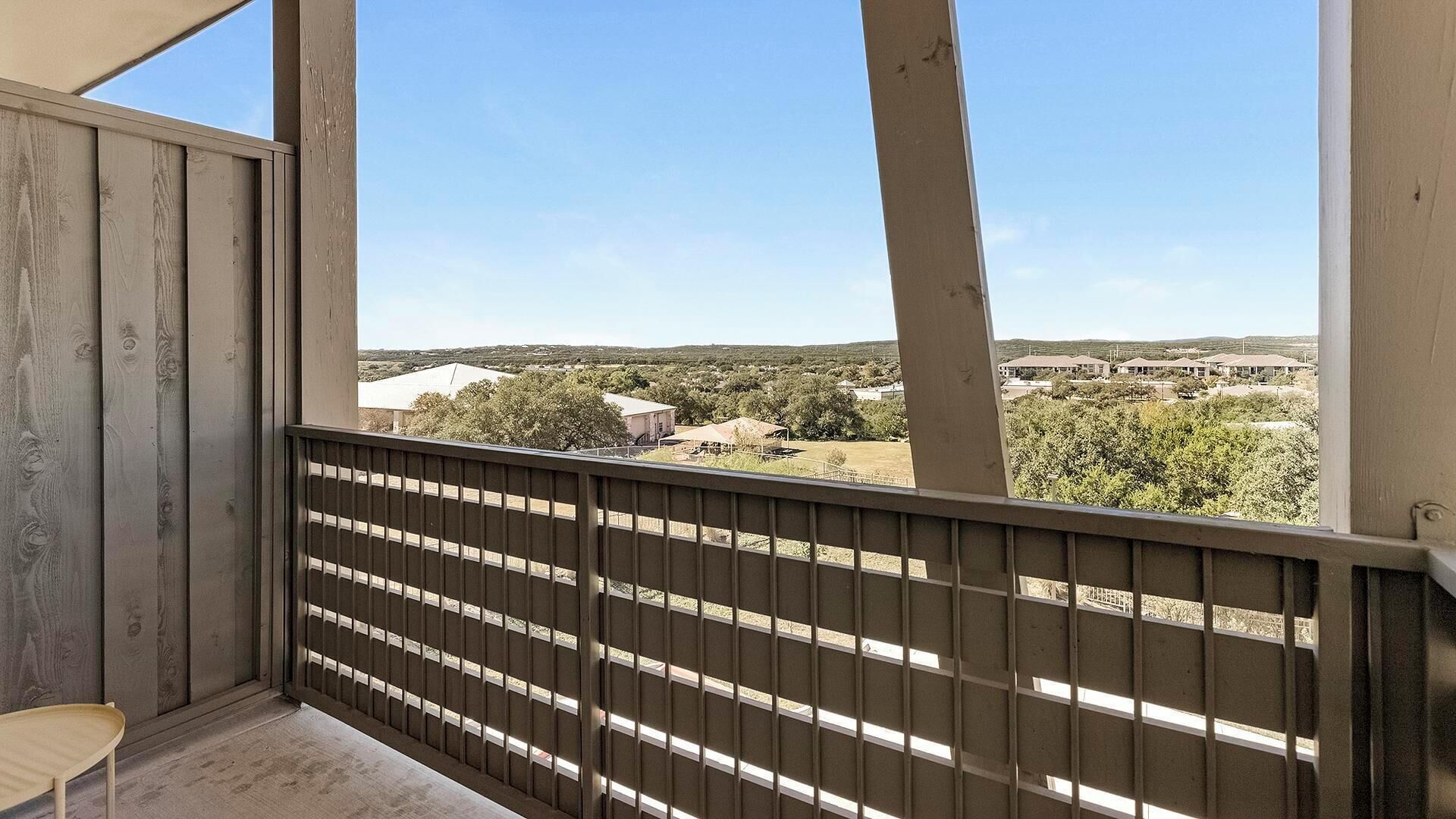 Ein Balkon mit Blick auf eine Wohngegend, Holzgeländer und ein kleiner Tisch.