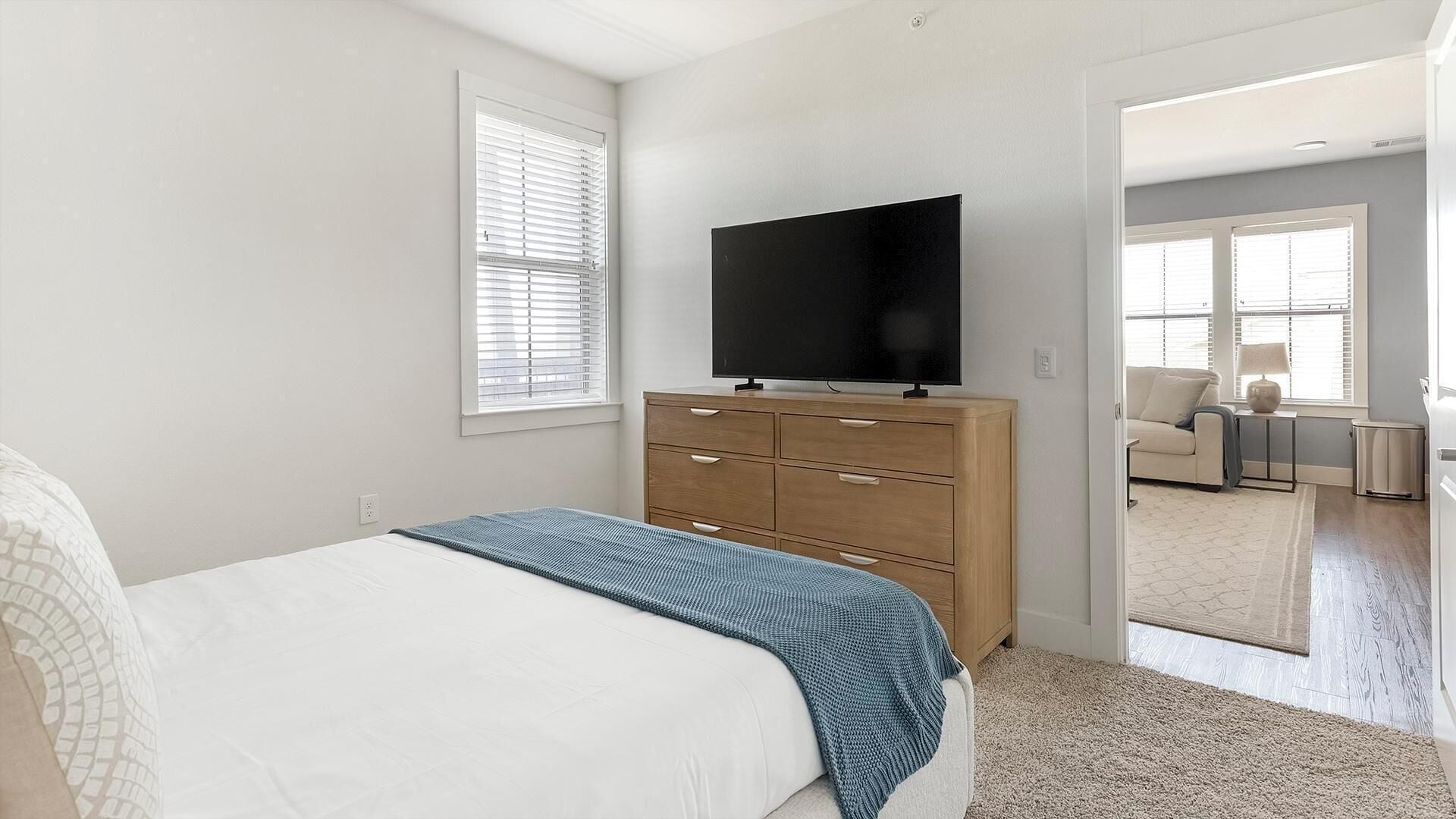 A bedroom with a bed, a dresser, a television, and a window.