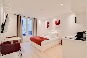 A modern hotel room with a bed, a desk, a chair, and a balcony view.