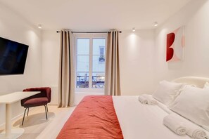 A modern hotel room with a bed, a desk, and a TV.