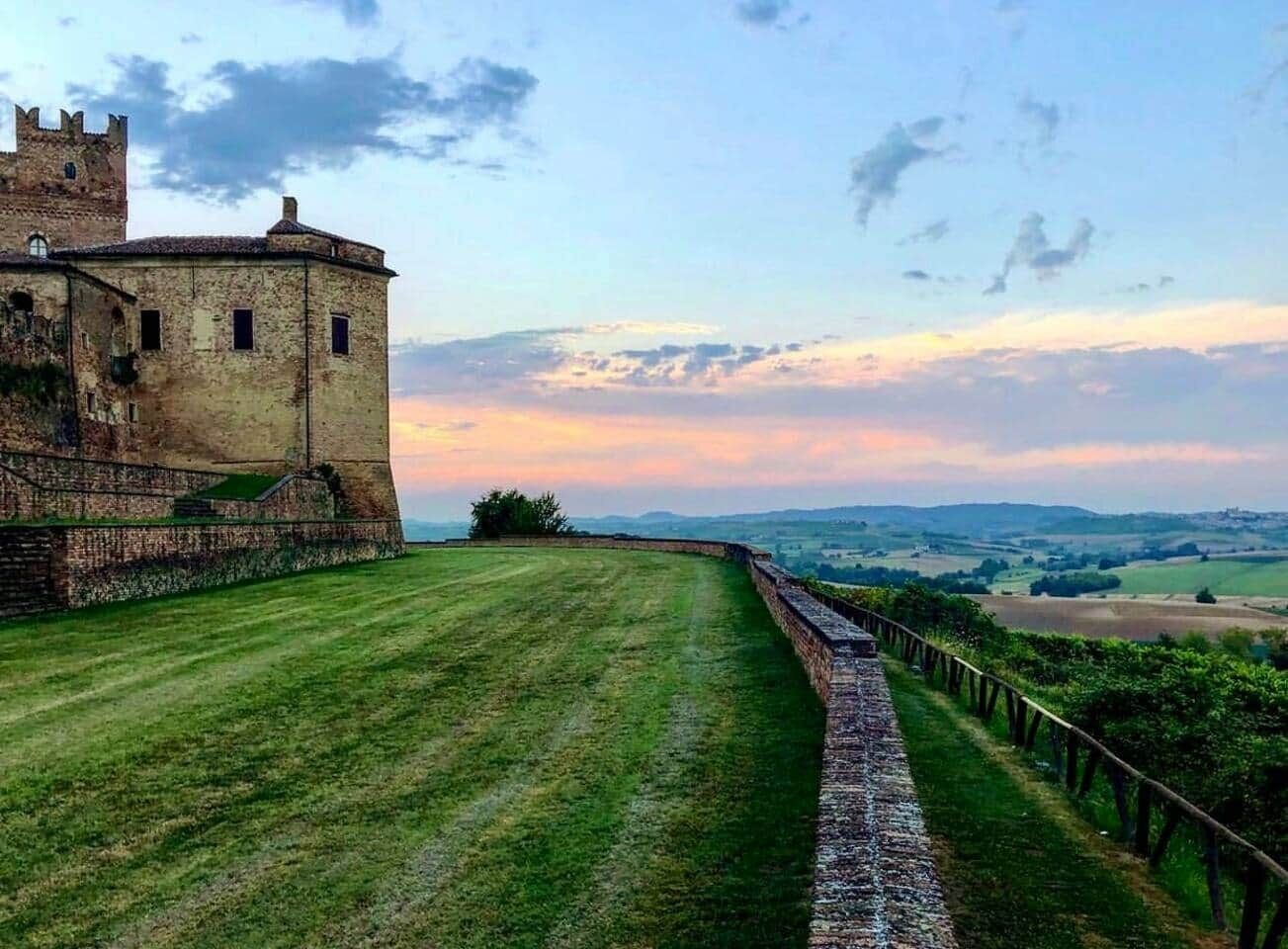 A castle with a grassy courtyard and a stone wall.