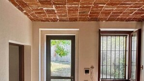 Une pièce avec un plafond en briques, une grande fenêtre avec des barreaux en métal, un radiateur et une table.