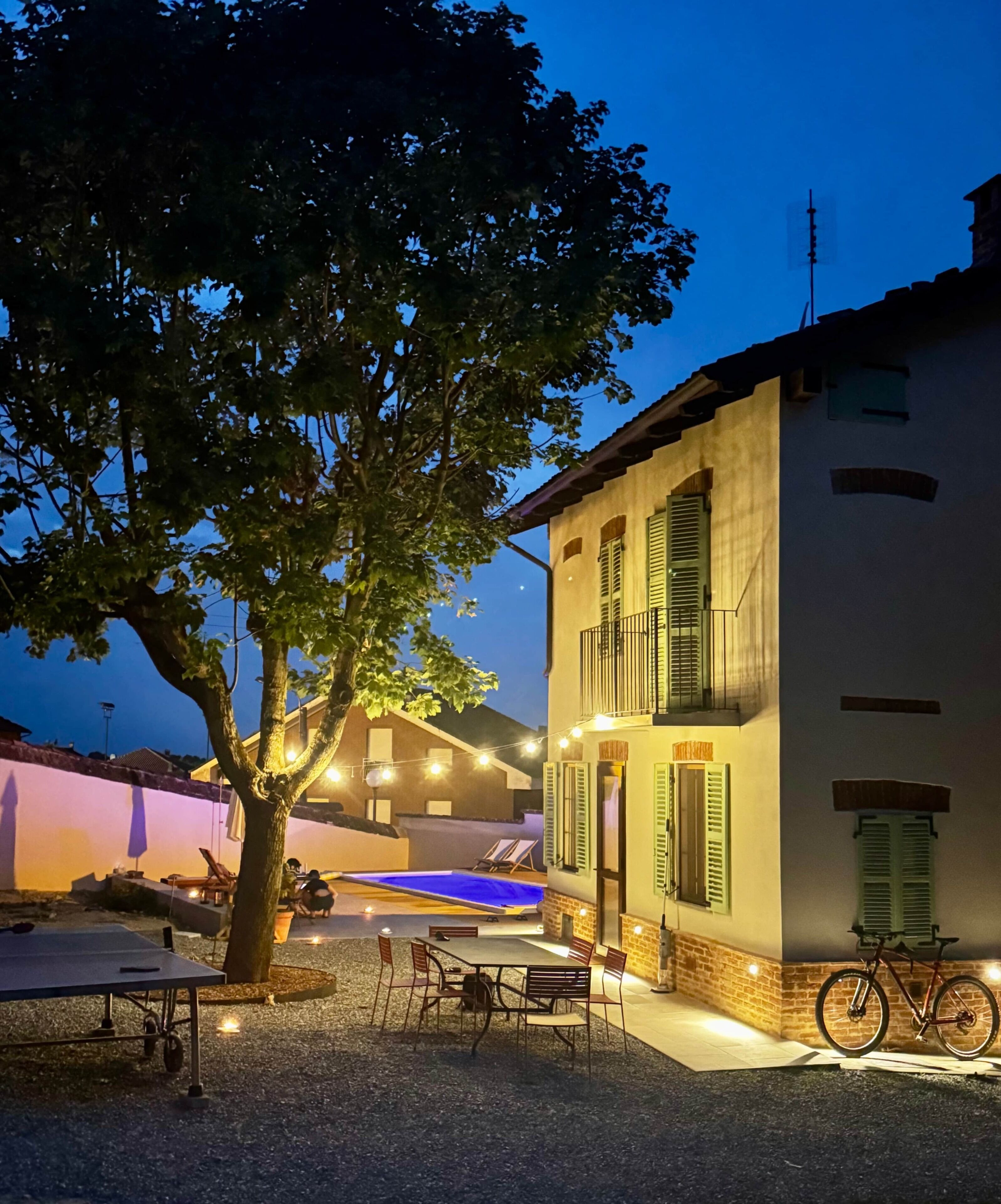 A building with a balcony, outdoor seating area, and a bicycle parked outside.