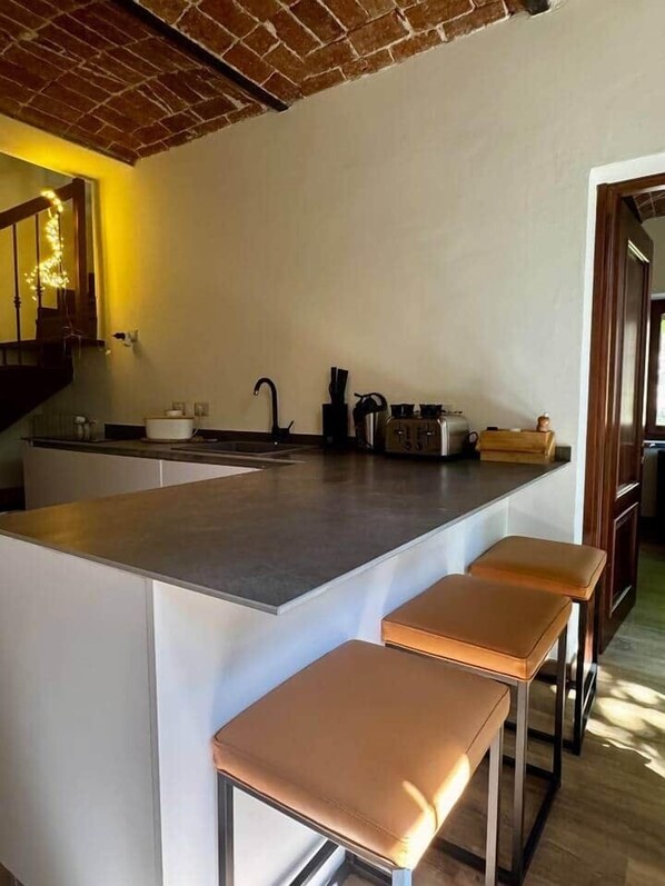 A kitchen with a central island, a sink, and two stools. - Independent Home with Private Courtyard - Monferrato (Montemagno)