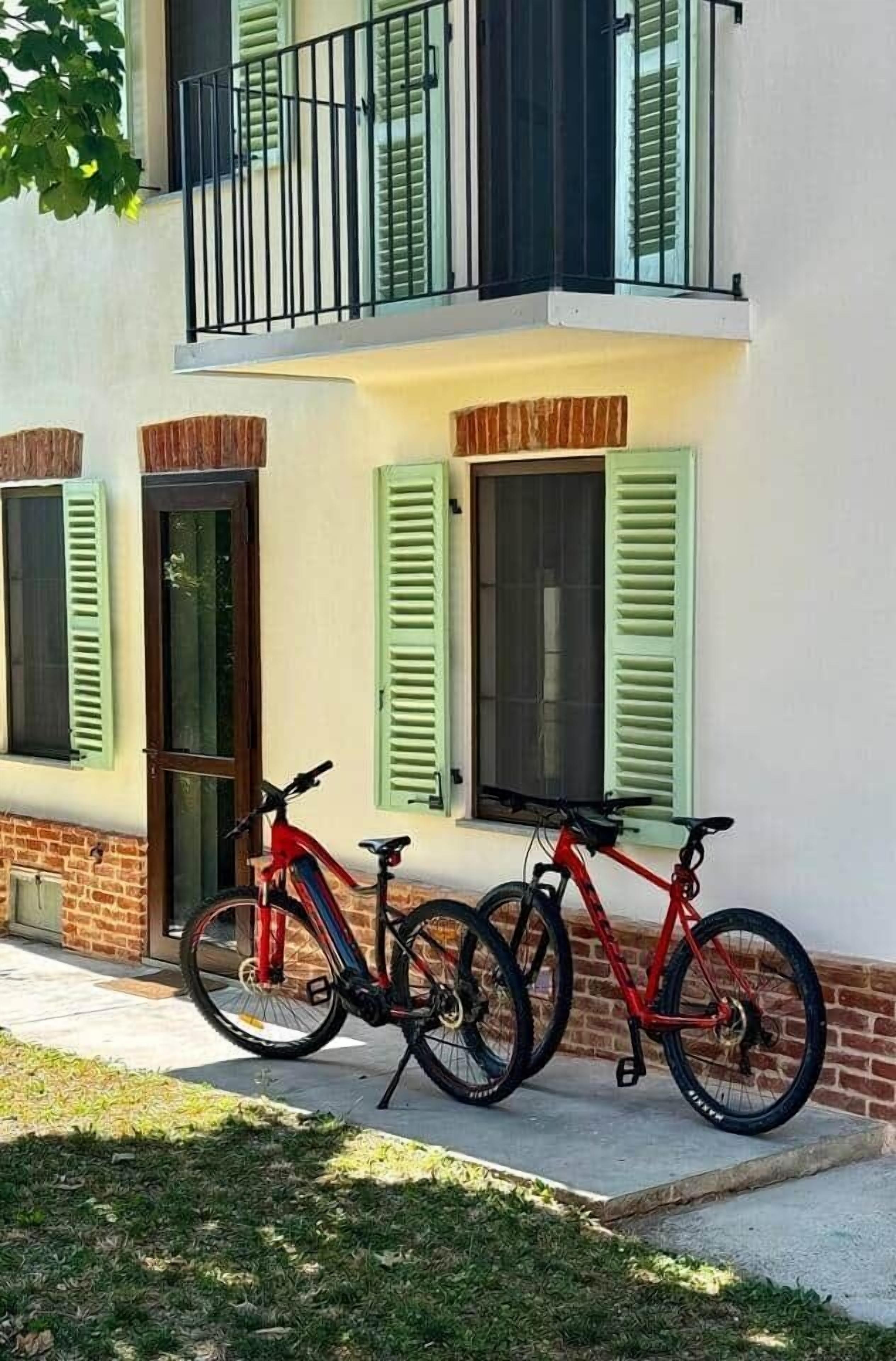 A two-story building with a balcony, green shutters, and a red bicycle parked outside.
