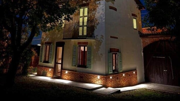 Une maison à deux étages avec un balcon, une antenne parabolique et des fondations en briques.
