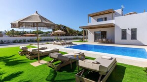 A modern house with a swimming pool, outdoor seating, and a well-maintained lawn. - Villa Kamelia Seaside Almyra by Villa Plus (Agkisaras)