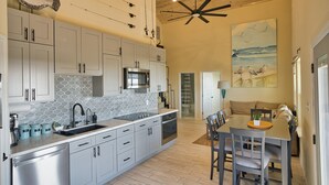 Une cuisine moderne avec des meubles blancs, un grand îlot central et un coin repas comprenant une table et des chaises.