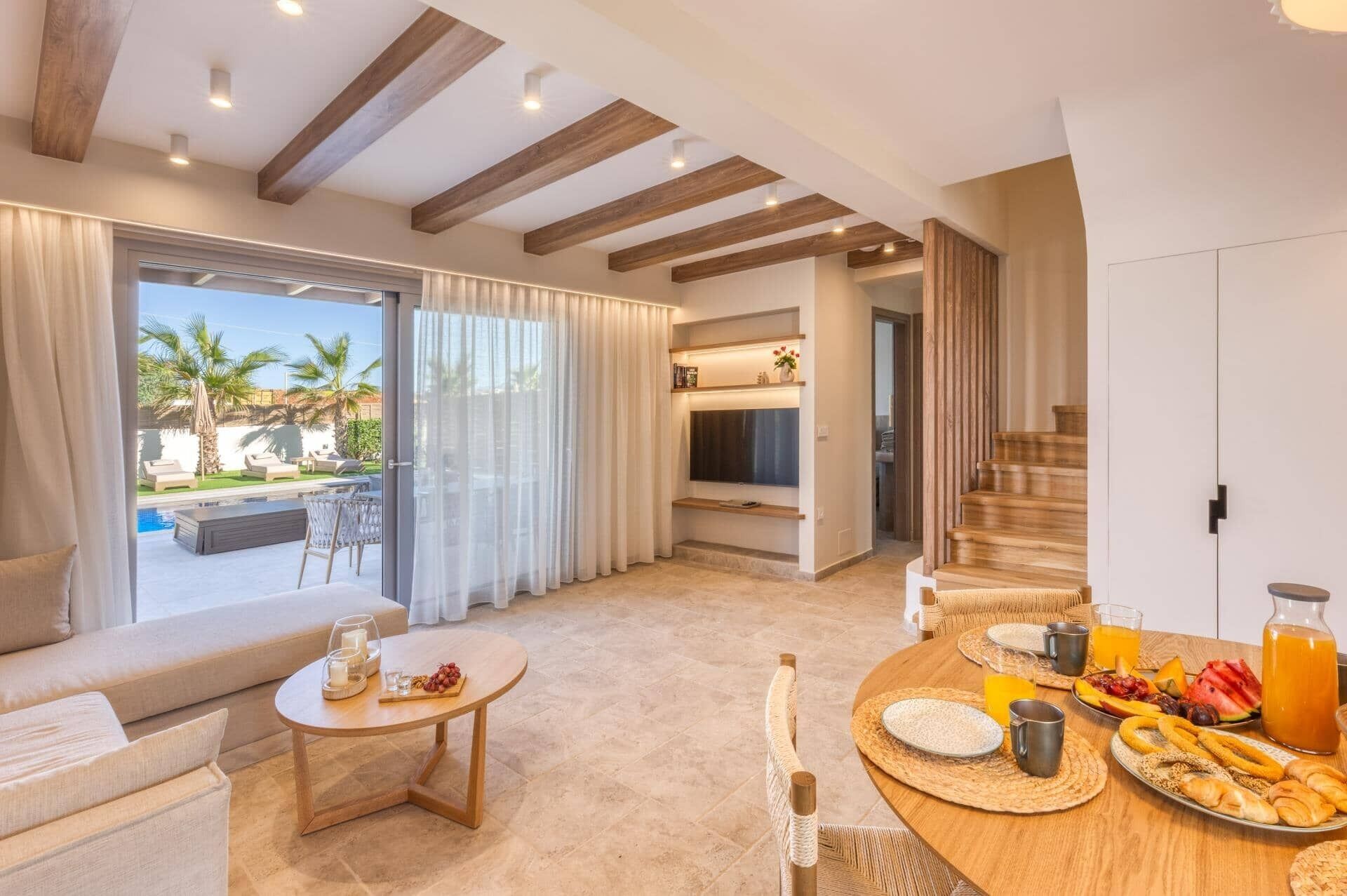 Ein modernes Wohnzimmer mit Blick auf einen Pool, einer Essecke mit Frühstück und einer Treppe.