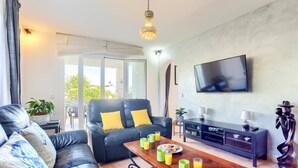A living room with a sofa, a coffee table with drinks, a TV, and a fireplace. - Villa Juan by Villa Plus (Cala d'Or)