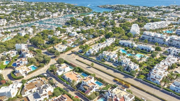 An aerial view of a coastal residential area with villas, a marina, and a road. - Villa Juan by Villa Plus (Cala d'Or)