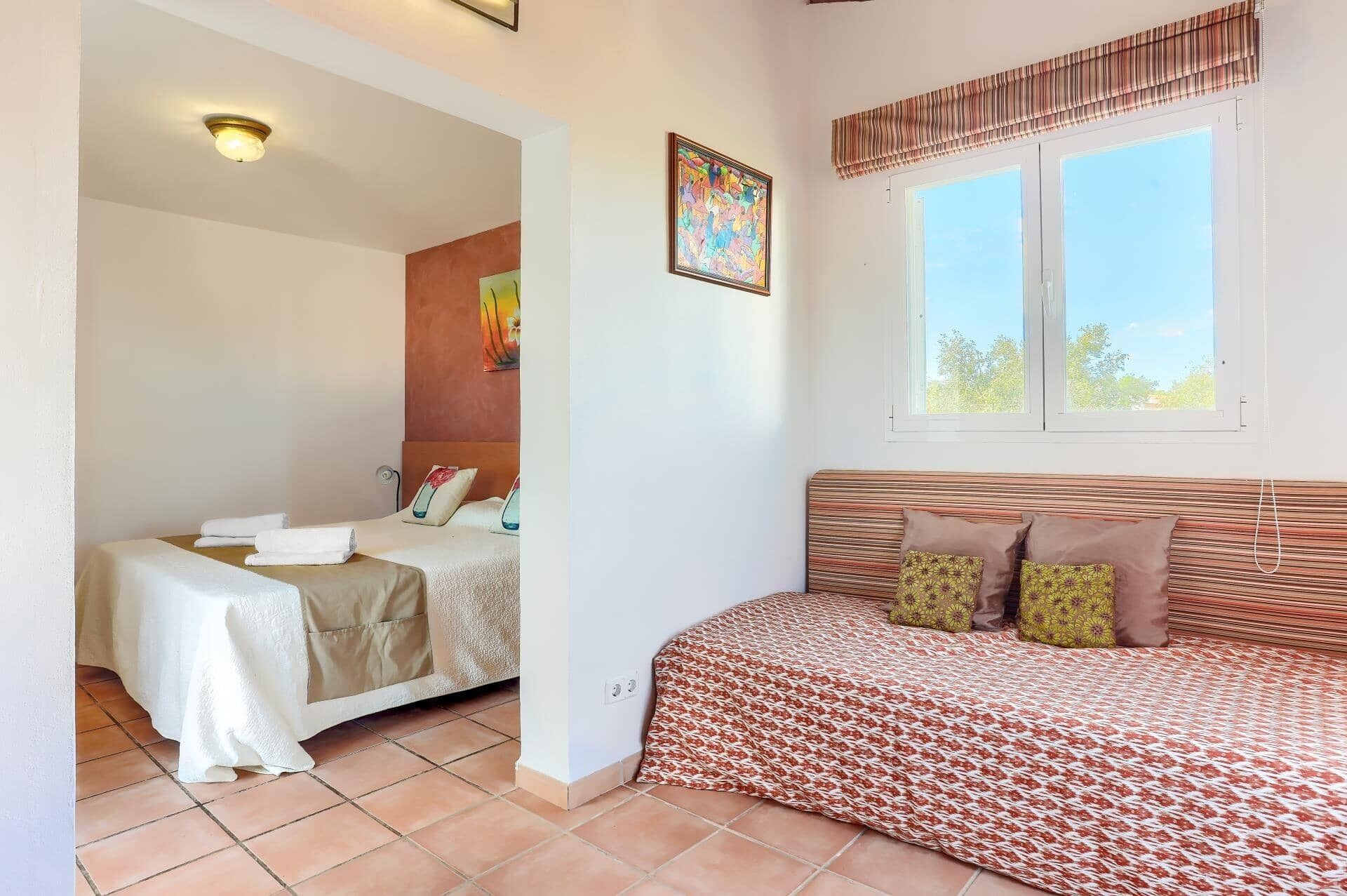 A room with a bed, a sofa, a window with blinds, and a ceiling light.