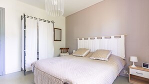A bedroom with a bed, nightstand, and a mirror on the wall. - Apartment in Saint-Pierre-d’Oléron with Private Terrace, Garden, and Wi-Fi (Saint-Pierre-d'Oléron)