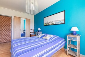 Een slaapkamer met een groot bed, een kledingkast, een nachtkastje en een aan de muur hangend schilderij.