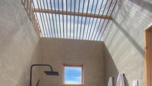 Un petit espace douche fermé, doté d’une fenêtre, d’un porte-serviettes et d’une baignoire.