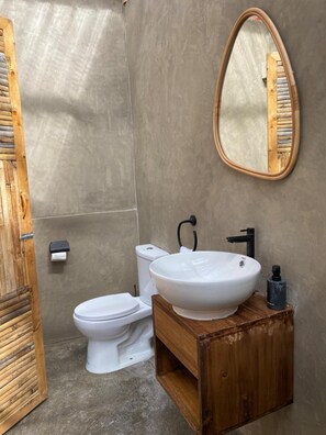 Een badkamer met een houten wastafelmeubel, een witte wasbak en een toilet.