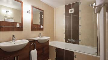 Un baño moderno con dos lavamanos, una bañera y una ducha.